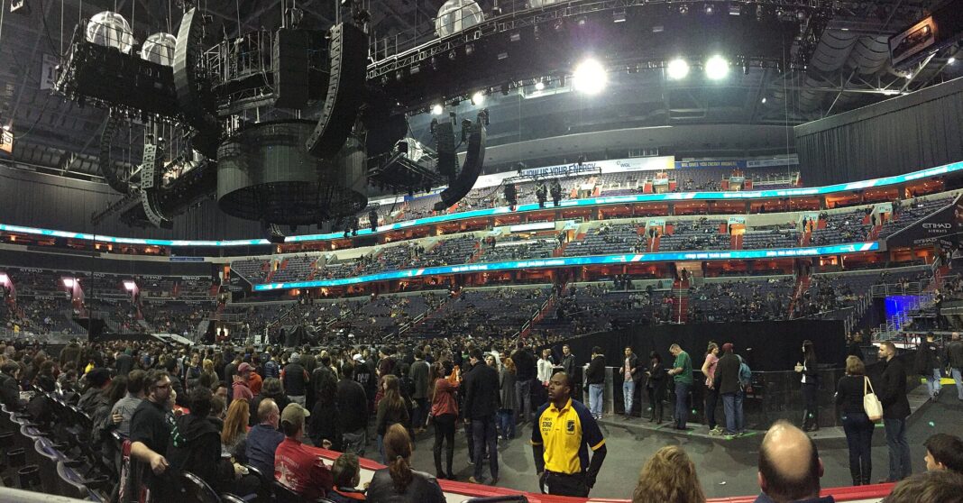 Fans standing on the floor of a Washington, D.C., arena before a concert, with lighting rigs hanging above
