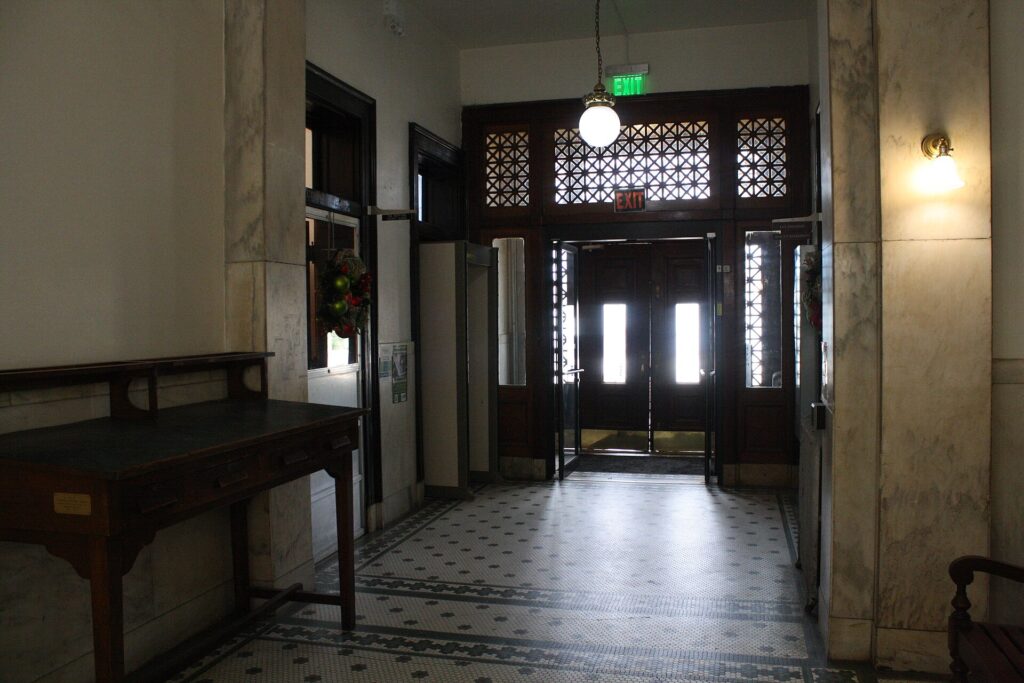 The tiled north entrance hall of the Monroe County Courthouse in Clarendon, Arkansas, with wooden doors and a hanging lamp
